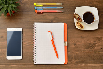 Open notebook with cup of coffee on wooden desk