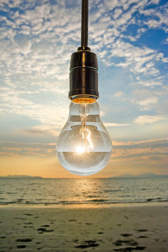 close up of vintage light bulb on background of sunset beach