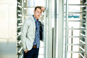 Fototapeta premium Elegant young handsome man wearing white jacket and jeans near building
