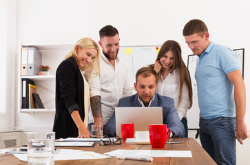 Happy business people team together look at laptop in office