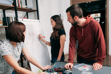 Wiring diagram drawing on whiteboard, teamwork. Creative engineers team creating electronic scheme...
