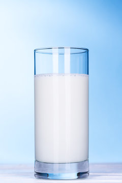 Glas Milch auf hell blau Hintergrund.