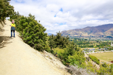 Man is climbing on the mountain with little girl on the shoulders. lake Wanaka town. New Zealand