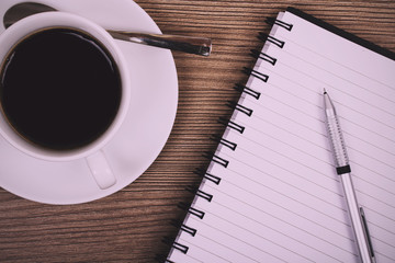 Cup of black coffee and notebook on wooden surface Vintage Retro