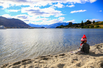 Fototapeta premium Little girl is playing by the water of Lake Wanaka, New Zealand