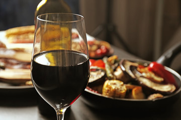 Glass of wine and grilled vegetables on served table
