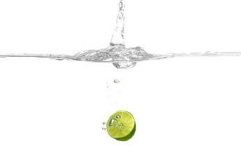 Lime falling into water on white background