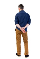 Naklejka premium Back view of man . Standing young guy. man in a blue shirt with the sleeves rolled up is looking pensively into the distance.