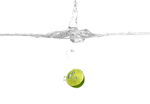 Lime falling into water on white background