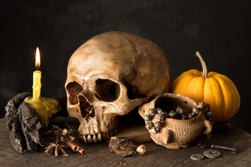 still life photography : old human skull with pumpkin, rosary, herb and Lighted candle on old wood...