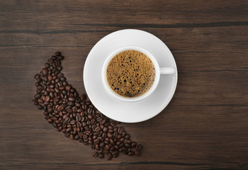 Cup of coffee with beans on wooden background