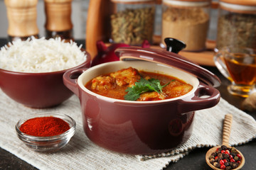 Tasty dinner with chicken curry in saucepan and rice in bowl