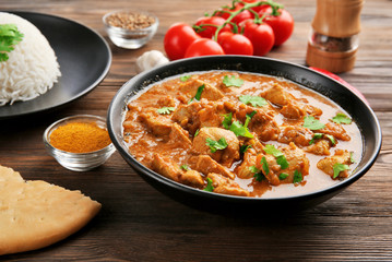 Tasty dinner with chicken curry in bowl on wooden background - obrazy, fototapety, plakaty