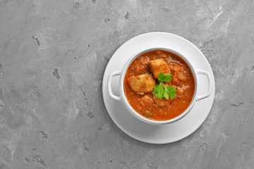 Tasty chicken curry in soup plate on grey background