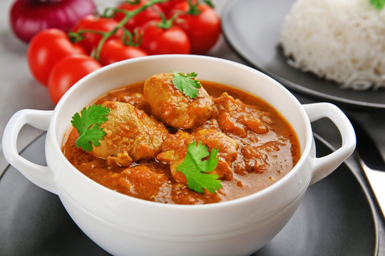 Tasty chicken curry in soup plate on grey background