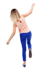 Balancing young woman. or dodge falling woman. Isolated over white background. The blonde in a pink t-shirt balancing on his leg.