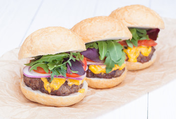 hamburgers pepper cheese onions sauce tomatoes on paper