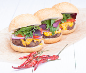 hamburgers pepper cheese onions sauce tomatoes on paper