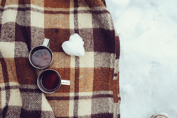 winter picnic on the snow. Hot tea, thermos and snowball heart on cozy warm blanket. Outdoor...