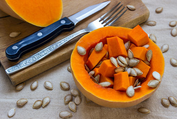 Sliced raw orange Pumpkin. Knife and fork on a wooden cutting bo