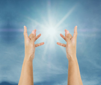 Hand trying to reach on the sky with sun rays
