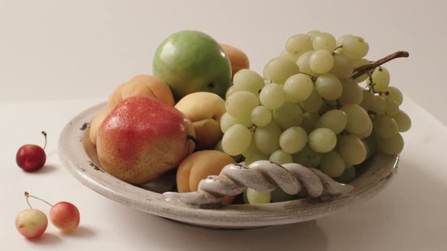 turning plate with fruit on white background, apear, grapes, peaches, apple