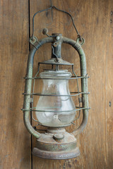 Old and rusty kerosene lantern hanging on the wooden wall