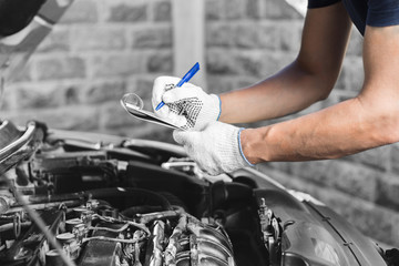 Auto mechanic checking car engine at the garage