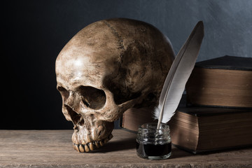 still life photography : skull with inkwell and old book on art dark background