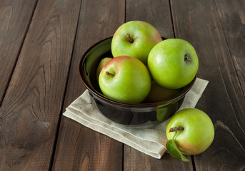 green apples in a bowl on a wooden background
