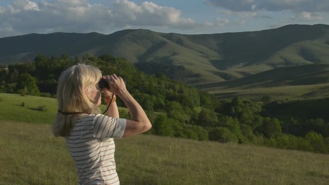 Woman is observing hills and peaks of Zlatibor Mountain with binoculars