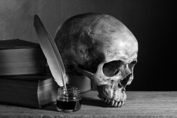 still life photography : inkwell and old book with skull on art dark background in black and white