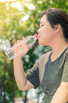 woman asian tubby white long hair girl drinking water, drink water after work out exercising on morning park.