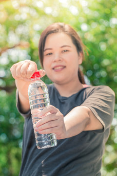 fitness asian white fatty woman with drinking water sun light morning effect selective focus at water bottle