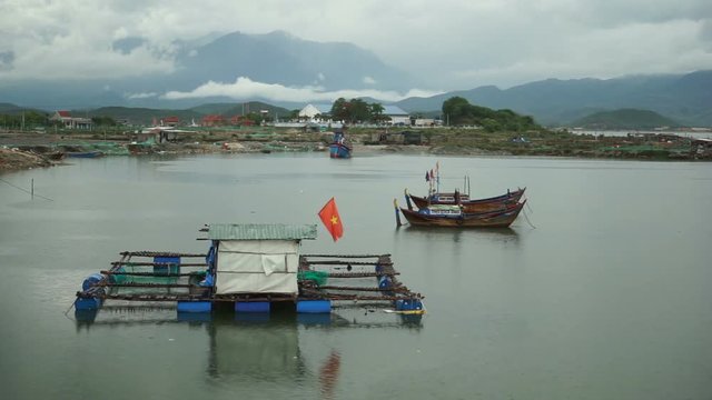 The small mooring with national flag of Vietnam on water for local fishing boats. Two ships are parked sideways 