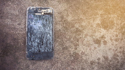 Broken smartphone on the cement floor with broken display.