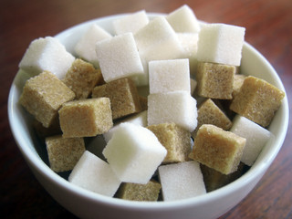 Cubes of white and brown sugar in a ceramic bowl
