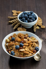 cereal flakes with blueberries and nuts on a dark wooden table