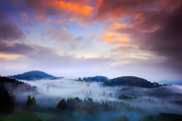 Foggy morning with beautiful orange clouds. Cold misty foggy morning in a fall valley of Bohemian Switzerland park. Hills with fog, landscape of Czech Republic, National Park Ceske Svycarsko