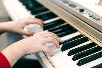 Girl's hands playing piano, selective focus