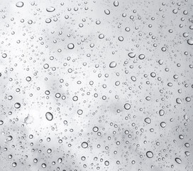 Drops of rain on glass , rain drops on clear window / rain drops with clouds / water drops on glass after rain background / water drops / Small water drops on the glass.