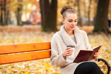 Obraz premium Pretty caucasian female drinking coffee and reading