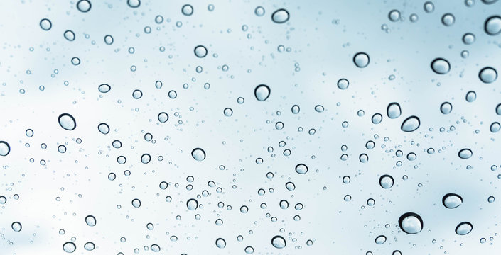 Drops of rain on glass , rain drops on clear window / rain drops with clouds / water drops on glass after rain background / water drops / Small water drops on the glass.