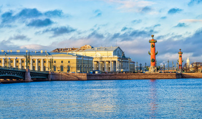 Naklejka premium Saint Petersburg, Russia. The view of the Spit of Vasilievsky island with the Old Stoch Exchange building and the Rostral columns at very cloudy winter day. Shot from the opposite side of the river.