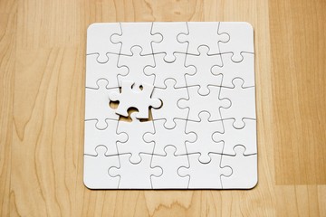 Letztes Teil eines weißen Puzzles auf Holzuntergrund