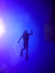     A backlit scuba diver silhouette. View of the scuba diver gear, fins and bubbles underwater in the deep blue sea of Limassol, Cyprus against the sunlight. 