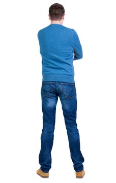 Back view of handsome man in blue pullover looking up.   Standing young guy in jeans. Rear view people collection.  backside view of person.  Isolated over white background.