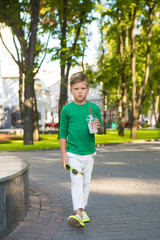 Stylish little boy with a serious expression going forward . In one hand he's got glasses , and other cocktail .