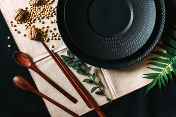 Set of black tableware with decor and cloth napkin on the black background