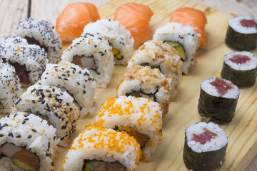 Different Sushi rolls,wasabi and ginger on a plate on wooden bac